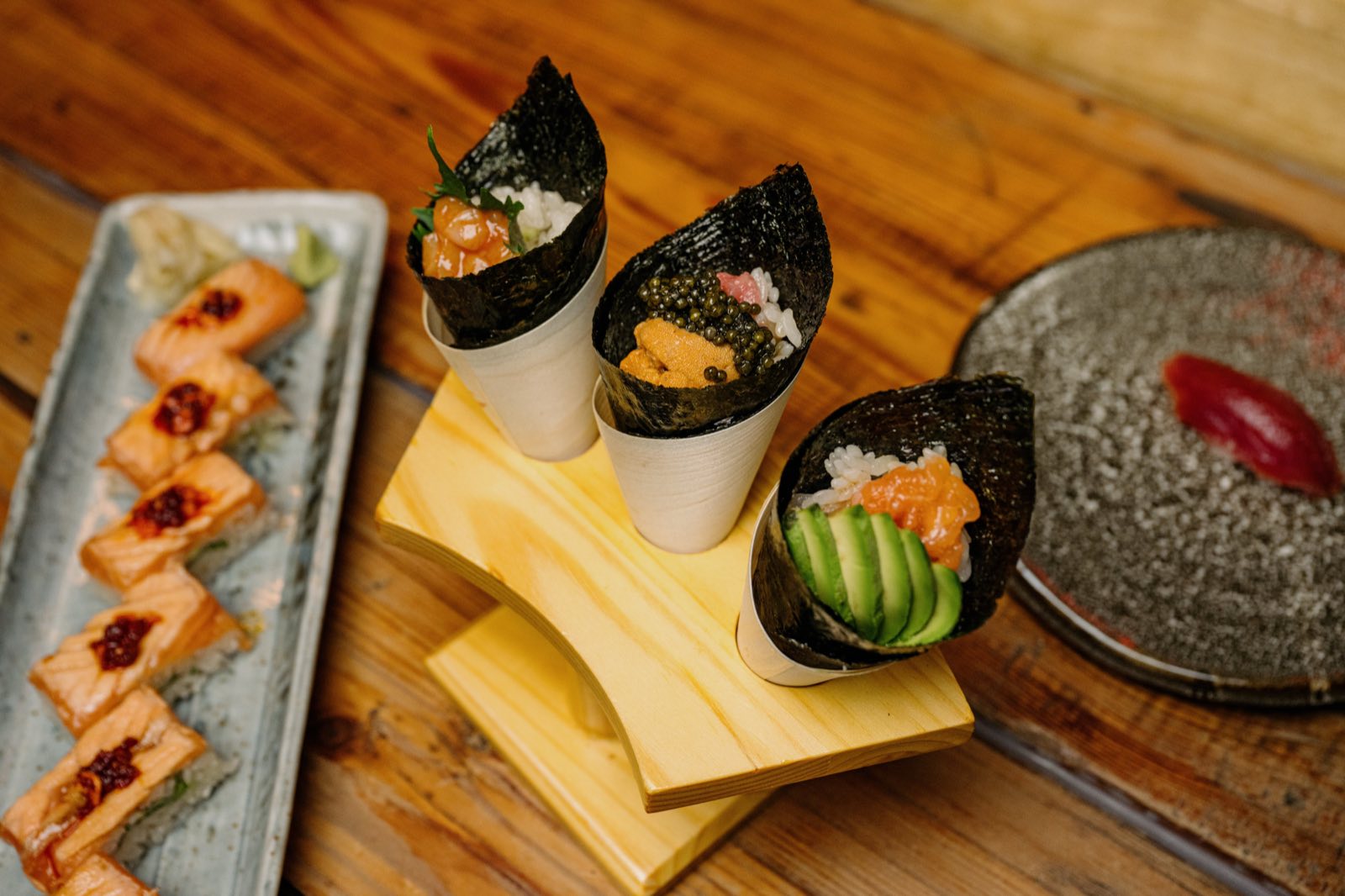 Three temaki hand rolls in a wooden holder